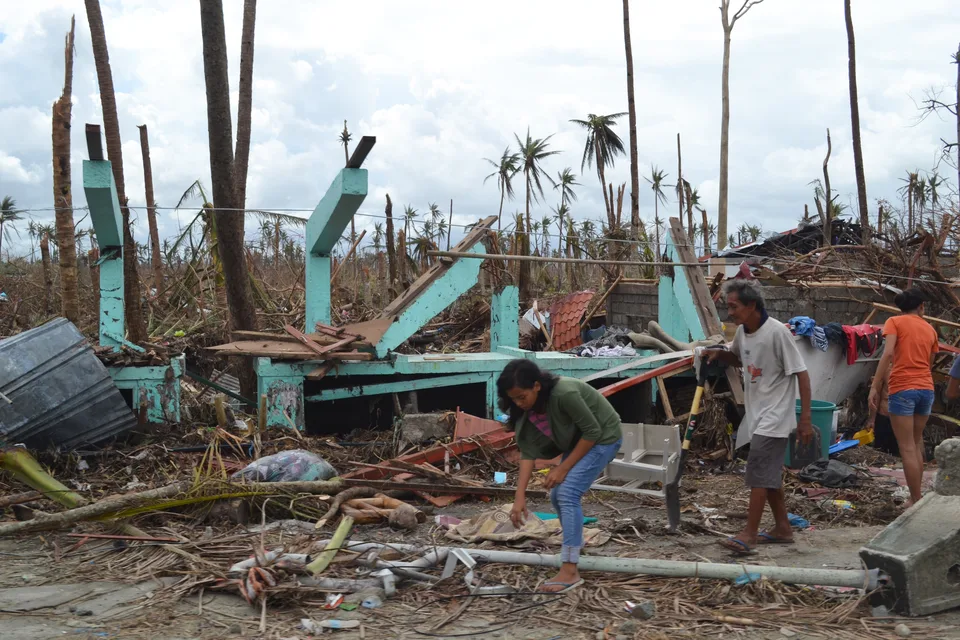 A destroyed house on the outskirts of Tacloban, Leyte, on 13 November 2013 after Typhoon Haiyan. Collapsed walls, scattered building materials and damaged trees are visible at this site.
